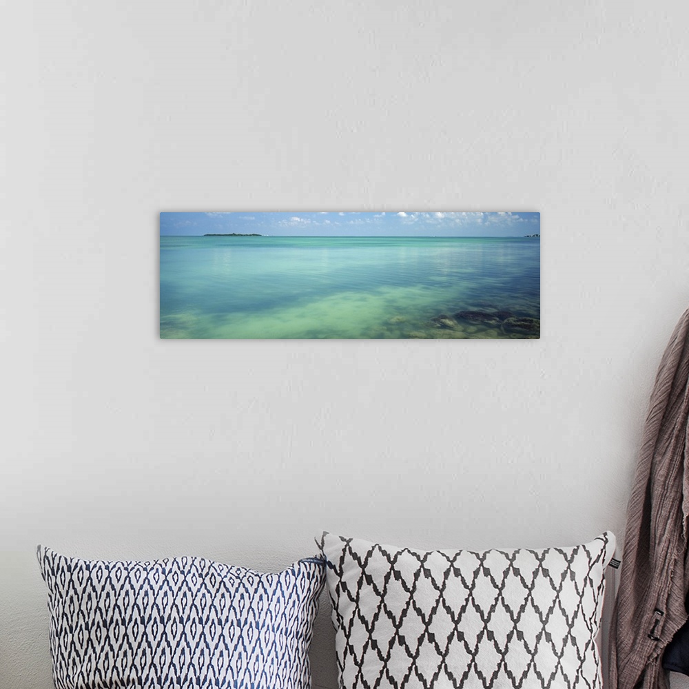 A bohemian room featuring Still, clear waters in a tropical sea in this panoramic seascape photograph.