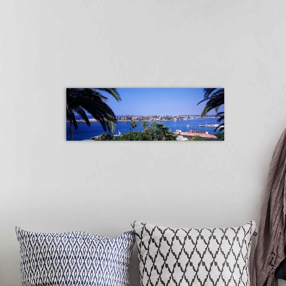 A bohemian room featuring Panoramic photograph of small town on an island seen from behind huge palm leaves.