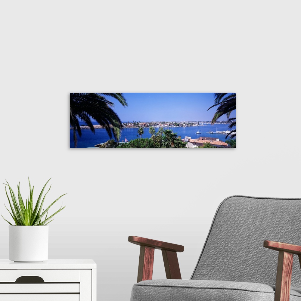 A modern room featuring Panoramic photograph of small town on an island seen from behind huge palm leaves.