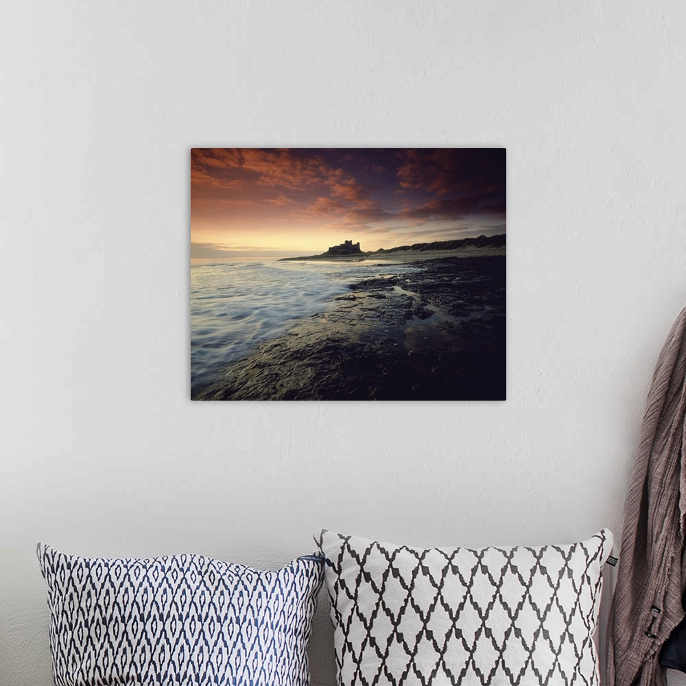 A bohemian room featuring Oversized landscape photograph of a rocky shoreline in England at sunset, Bam burgh Castle can be...