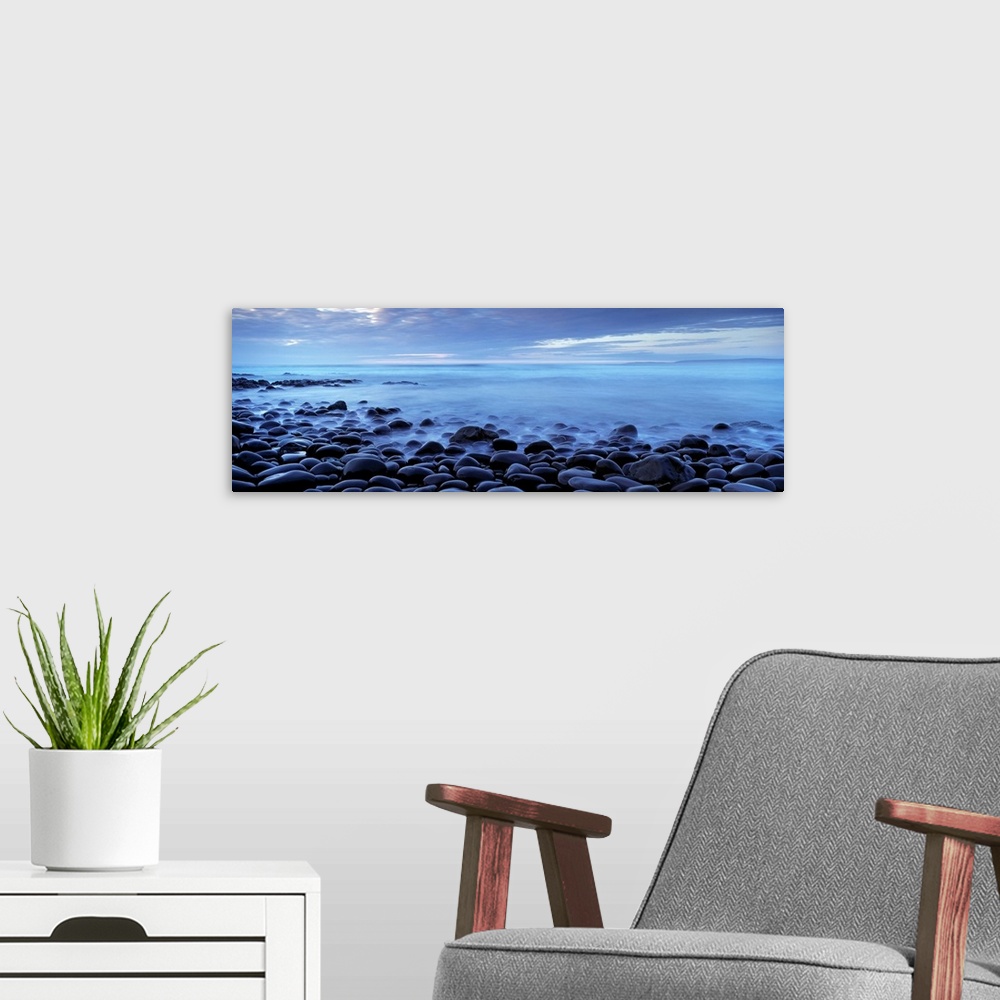 A modern room featuring Panoramic photograph shows the shores of a beach in the United Kingdom filled with smooth stones ...