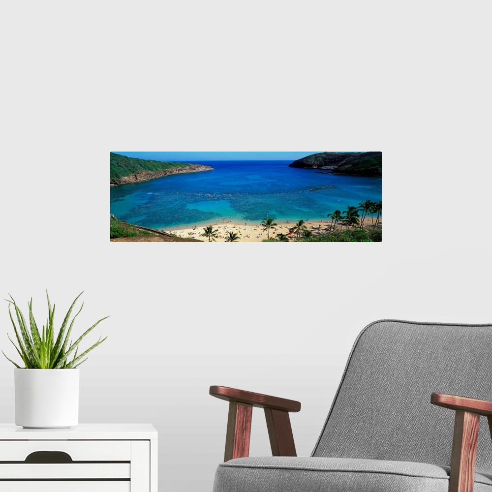 A modern room featuring High angle panoramic of a harbor on a tropical island and tourist sunbathing on the shore.