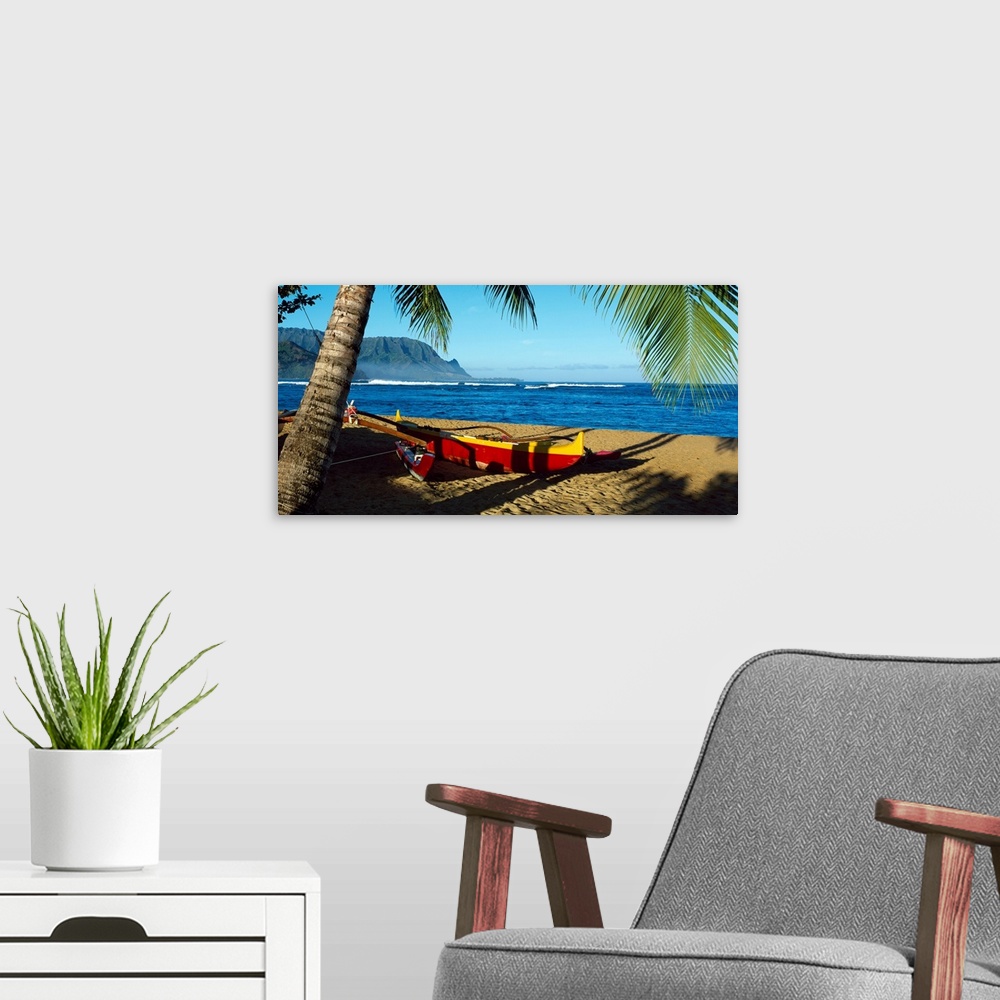 A modern room featuring Oversize wall art of a landscape photograph of a sailboat pulled up the shore and resting in the ...