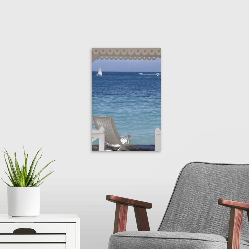 A modern room featuring Oversized, portrait photograph of beach chair beneath a canopy, looking toward clear blue ocean w...