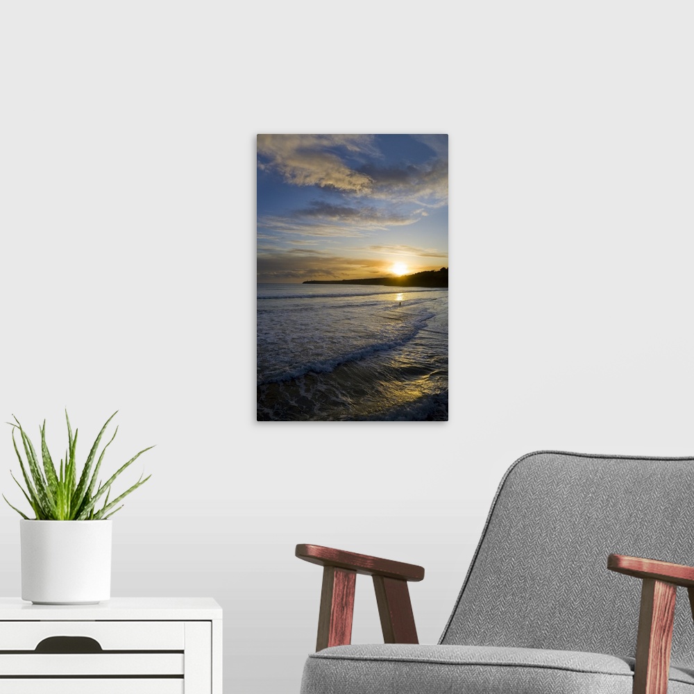 A modern room featuring This is a photograph of a sunset off the coast of Ireland with small waves crashing onto the beach.