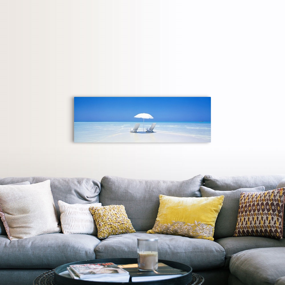 A farmhouse room featuring A panoramic photograph displaying two chairs sitting underneath an umbrella on a sandy beach in M...