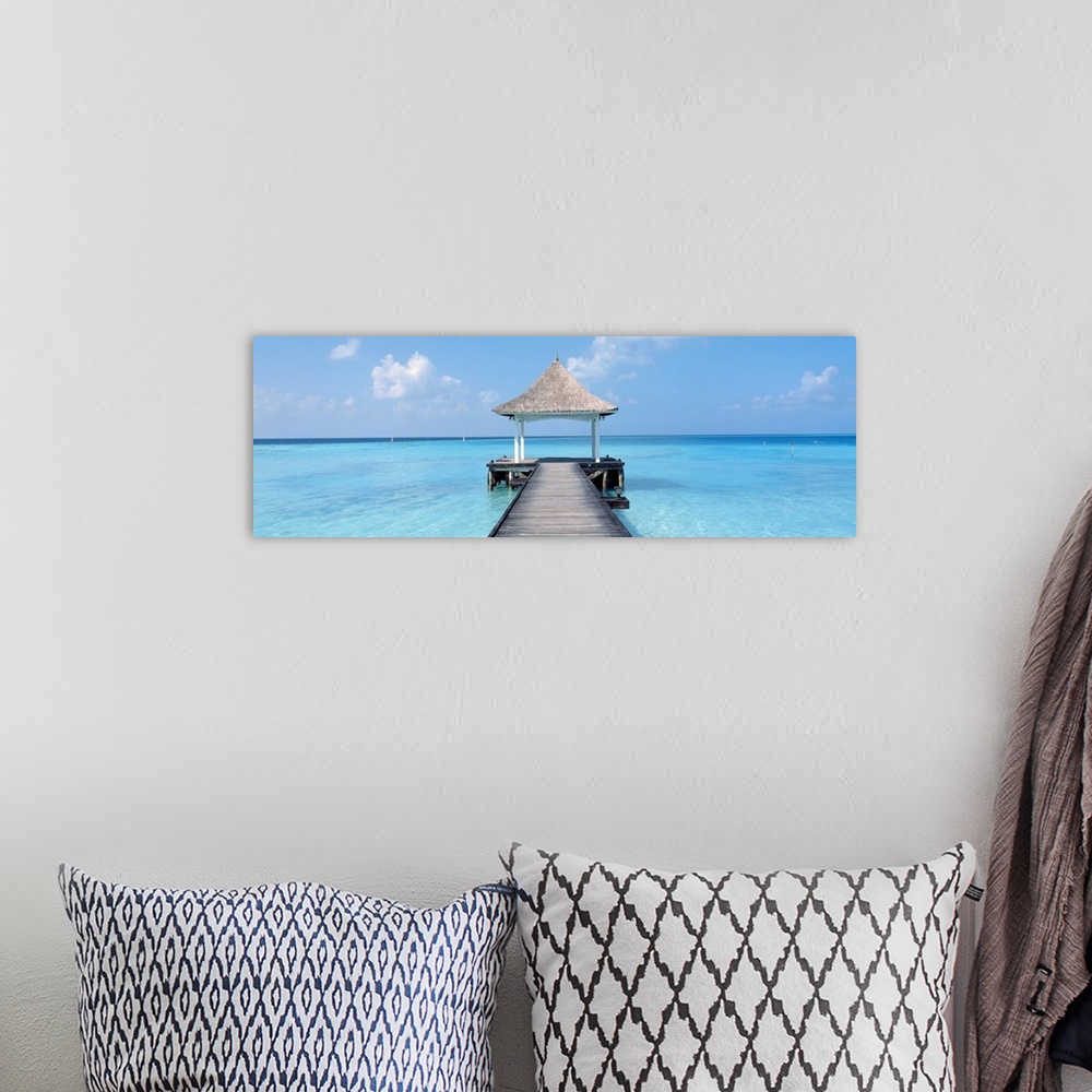 A bohemian room featuring Oversized panoramic photograph of a pier extending into the crystal clear waters of the Maldives,...