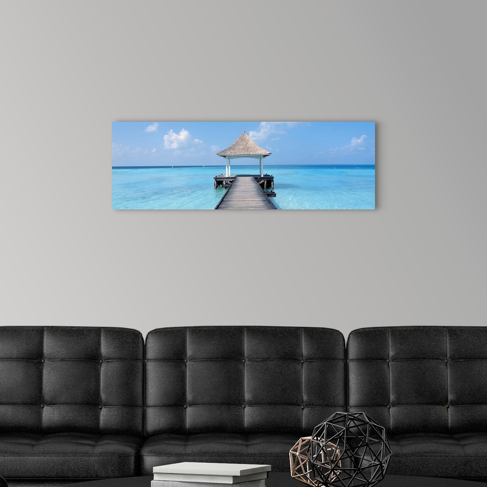 A modern room featuring Oversized panoramic photograph of a pier extending into the crystal clear waters of the Maldives,...