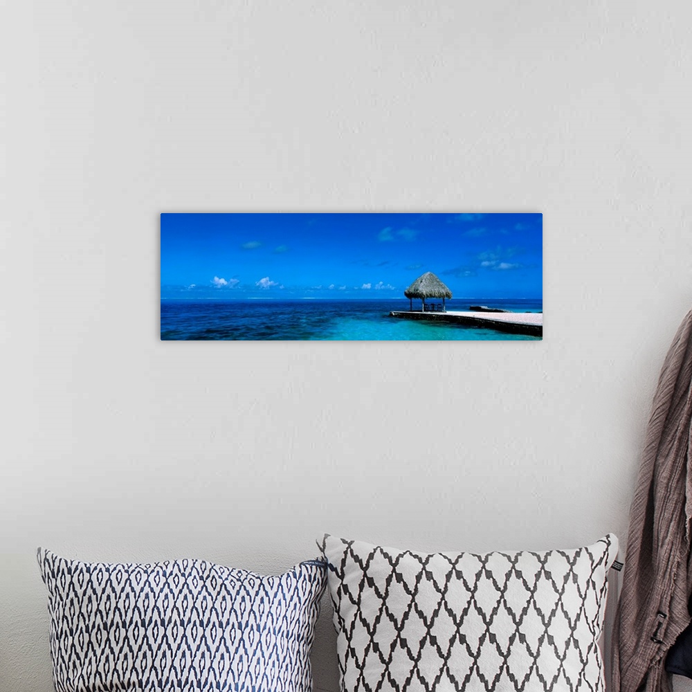 A bohemian room featuring This large wall art is a sweeping panoramic photograph of the ocean horizon and a single shady sh...
