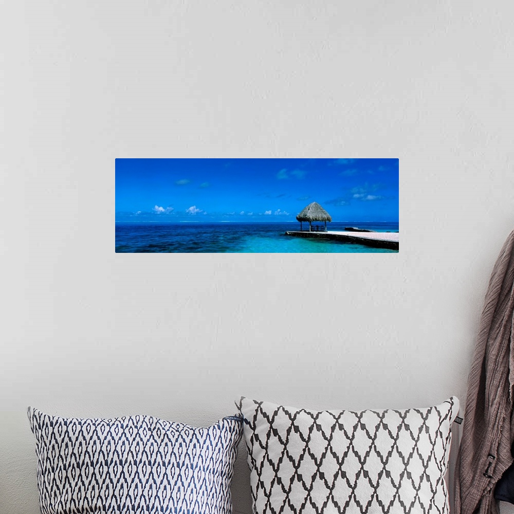 A bohemian room featuring This large wall art is a sweeping panoramic photograph of the ocean horizon and a single shady sh...