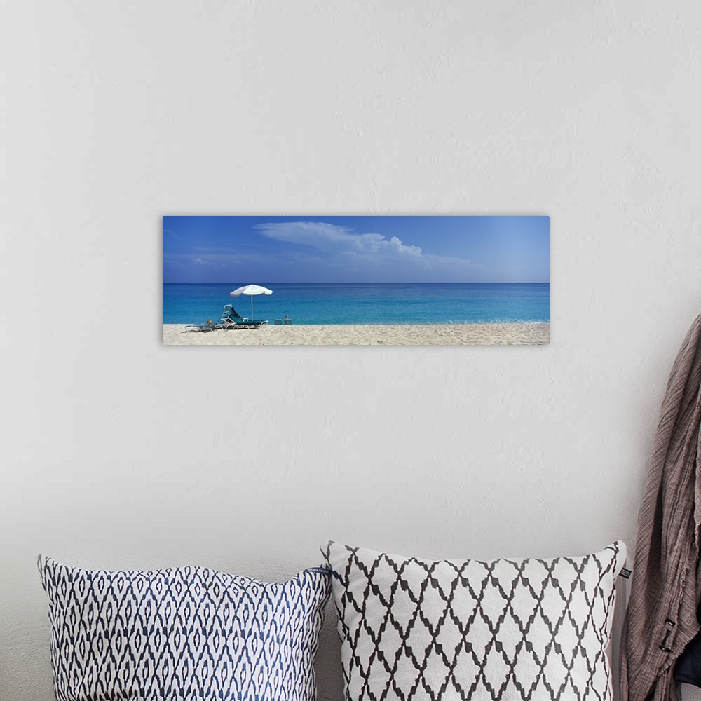 A bohemian room featuring Panoramic photograph of beach chairs and umbrella on sand with calm ocean in the distance.