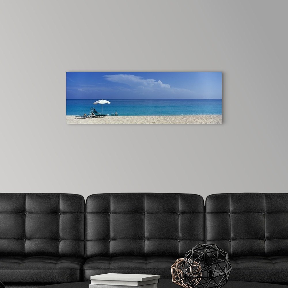 A modern room featuring Panoramic photograph of beach chairs and umbrella on sand with calm ocean in the distance.