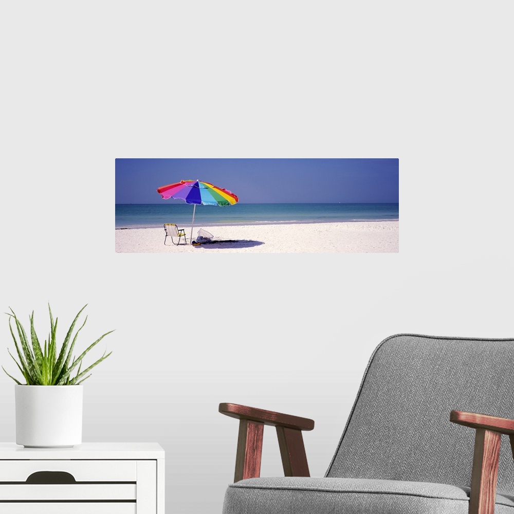 A modern room featuring Panoramic photograph of beach chair and parasol in the sand, with ocean fading into the distance....