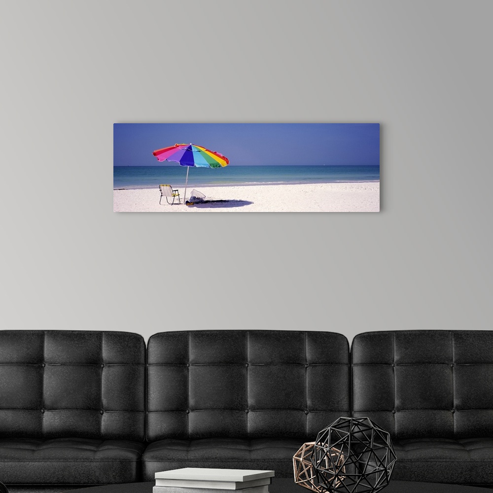 A modern room featuring Panoramic photograph of beach chair and parasol in the sand, with ocean fading into the distance....