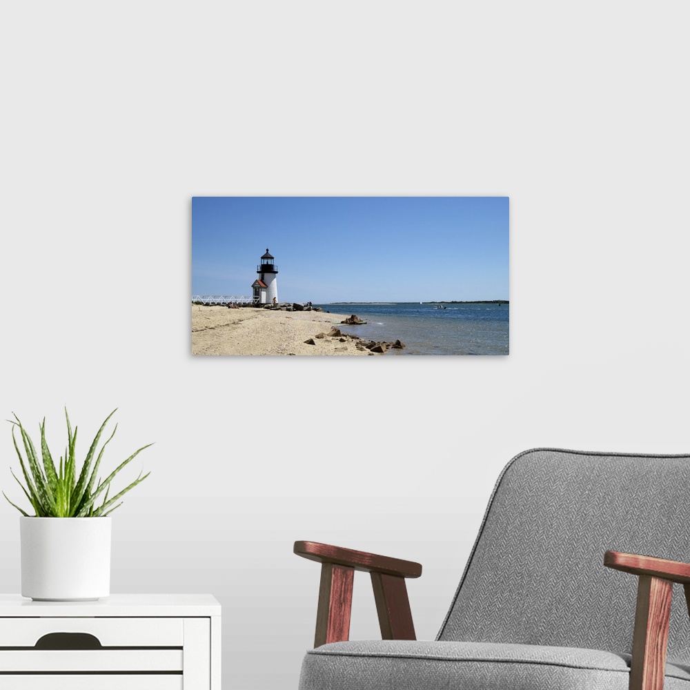 A modern room featuring Deocrative artwork for the home or office of a lighthouse sitting on the edge of the beach and th...