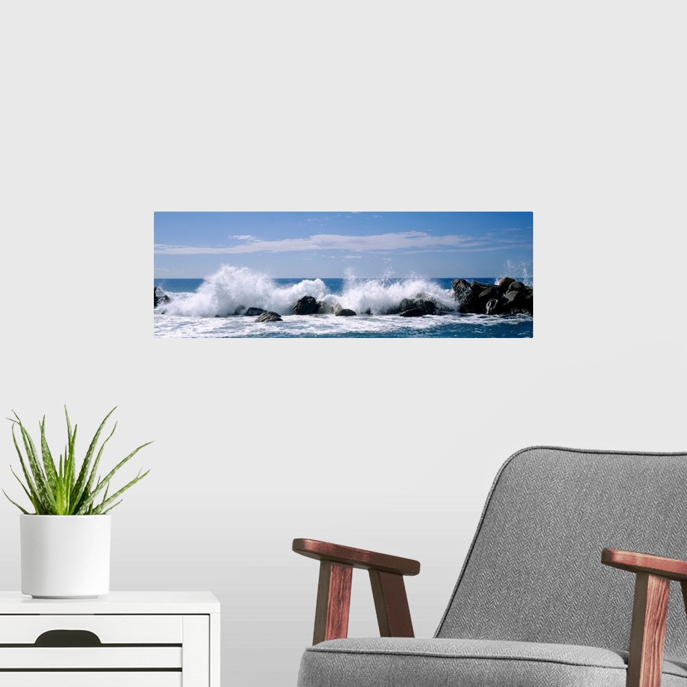 A modern room featuring Panoramic photograph of swells crashing against rocks under a cloudy sky.