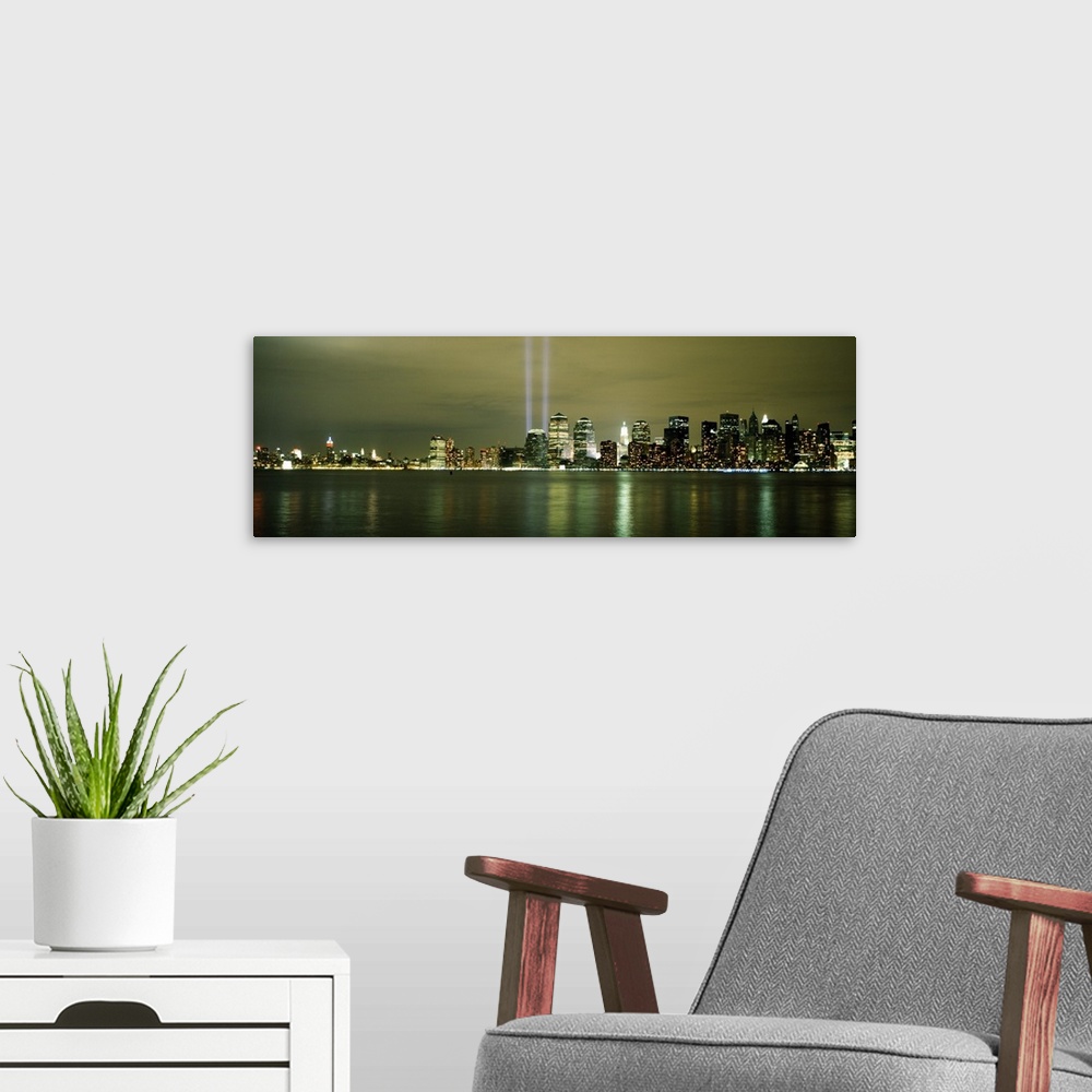 A modern room featuring Panoramic cityscape on canvas of NYC lit up with two beacons of light shooting upwards in place o...
