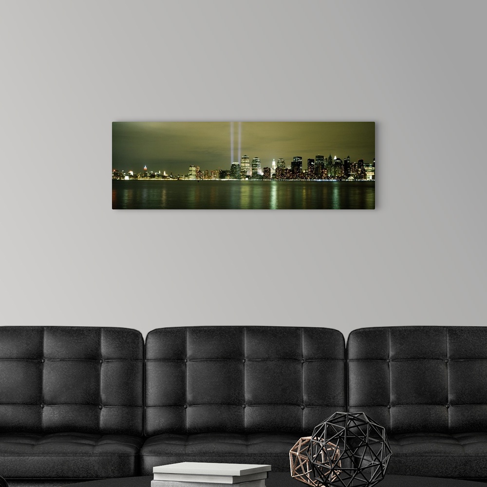 A modern room featuring Panoramic cityscape on canvas of NYC lit up with two beacons of light shooting upwards in place o...