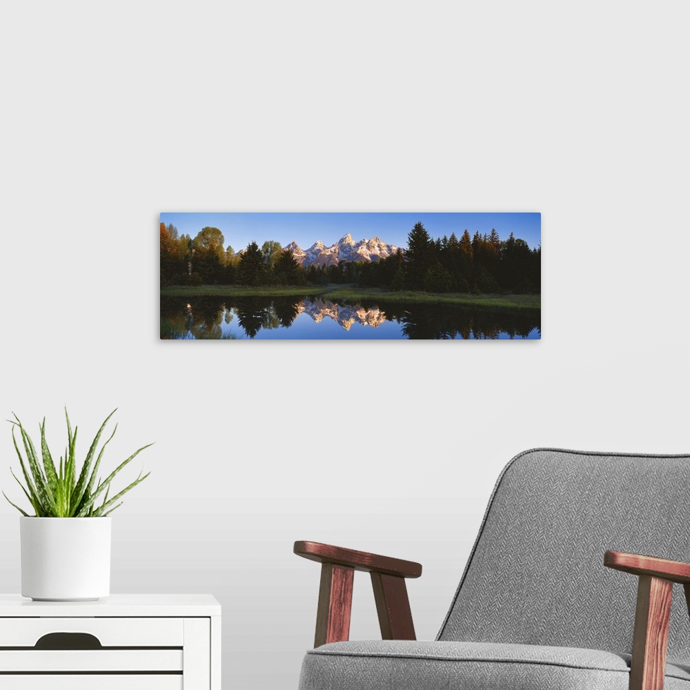 A modern room featuring Panoramic photo on canvas of a rugged mountain range in the distance of a tree line and a lake wi...