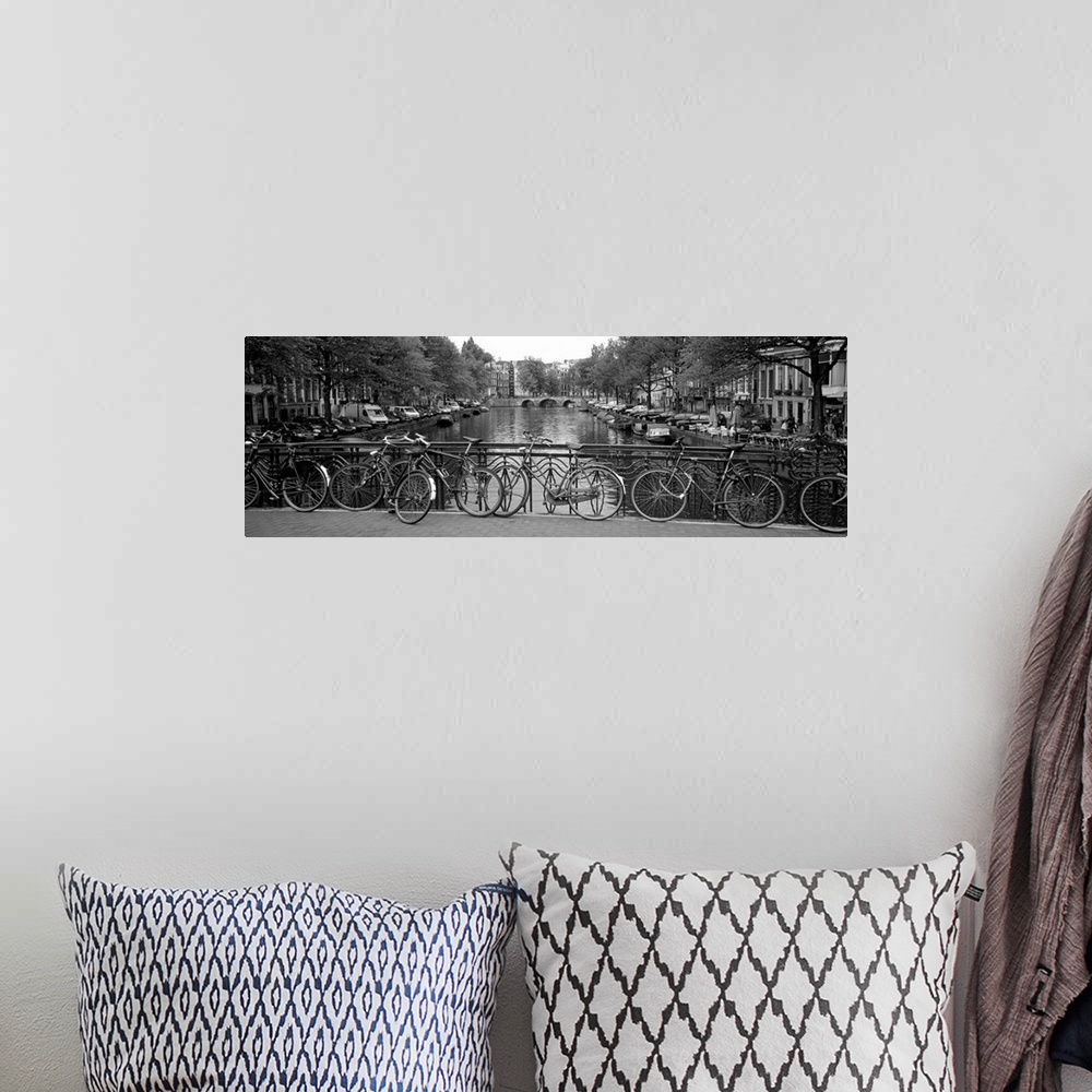 A bohemian room featuring Panoramic monochromatic photograph focuses on a group of bikes resting on an overpass over a rive...