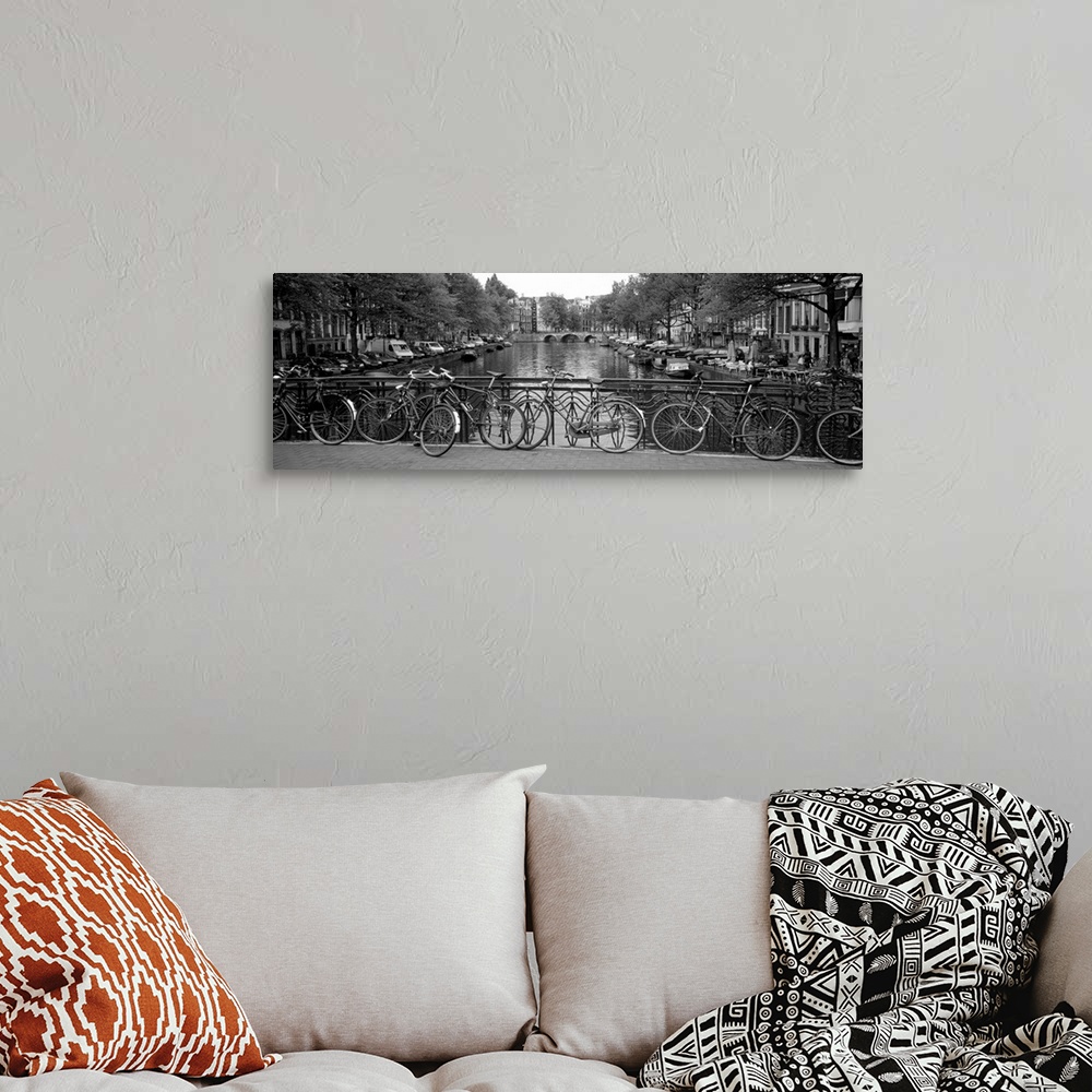A bohemian room featuring Panoramic monochromatic photograph focuses on a group of bikes resting on an overpass over a rive...