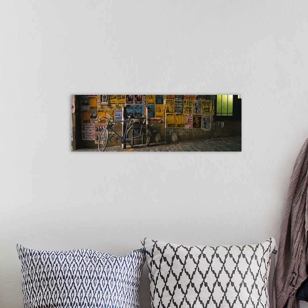 A bohemian room featuring This panoramic photograph is a cobblestoned street build on a slant and a wall covered in band po...