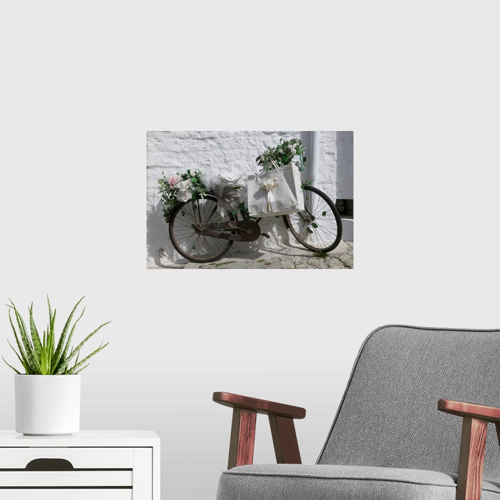 A modern room featuring A bike with rusty gears covered in beautiful roses with a decorative ribboned tote bag leaning ag...