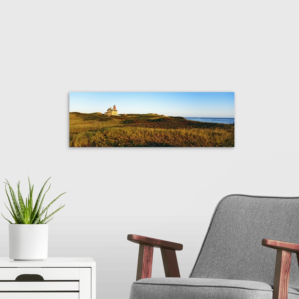 A modern room featuring A large lighthouse is photographed in panoramic view surrounded by open grassy land.