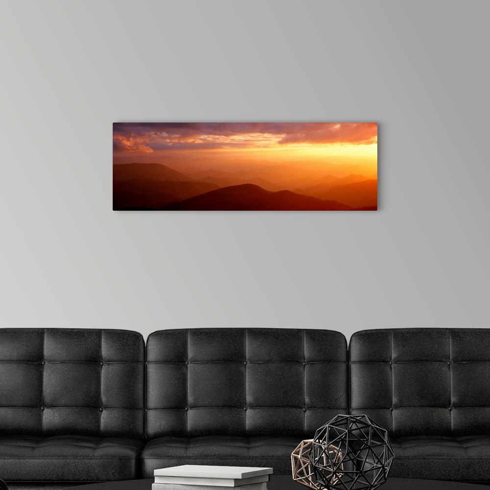 A modern room featuring Panoramic photograph shows the glow of the sun as it begins to set on a mountain range within Nor...