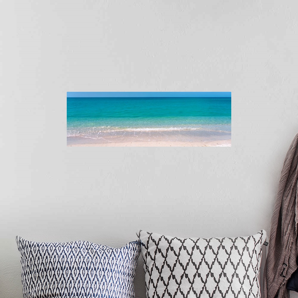 A bohemian room featuring A panoramic photograph of a calm sea of tropical colored water.