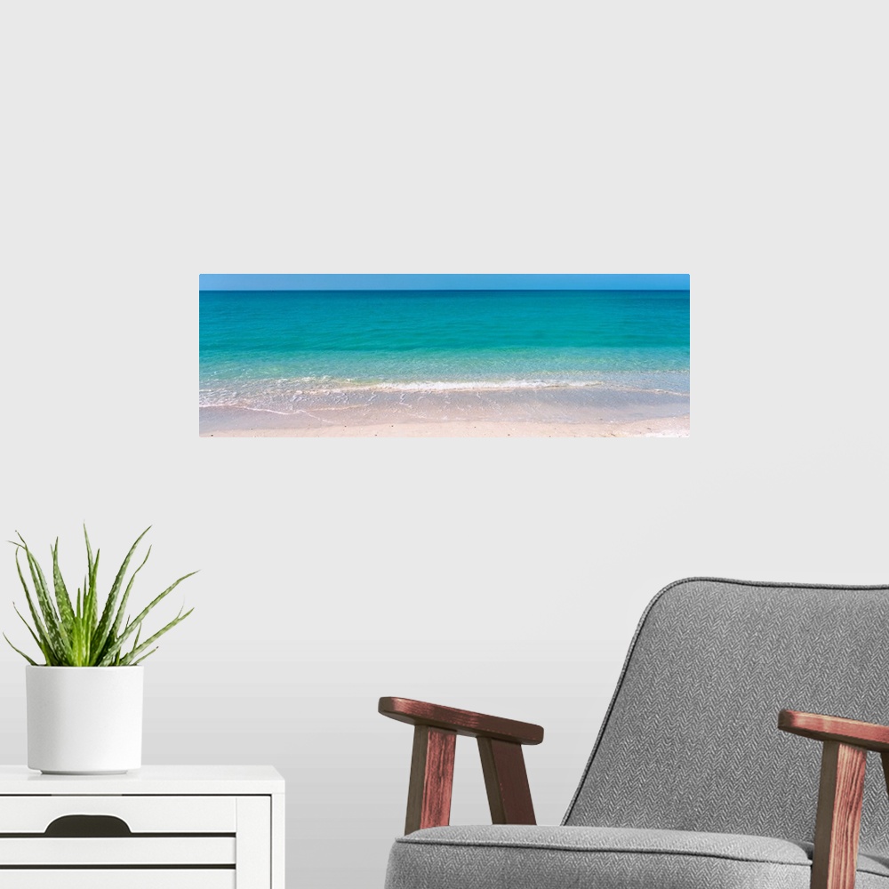 A modern room featuring A panoramic photograph of a calm sea of tropical colored water.