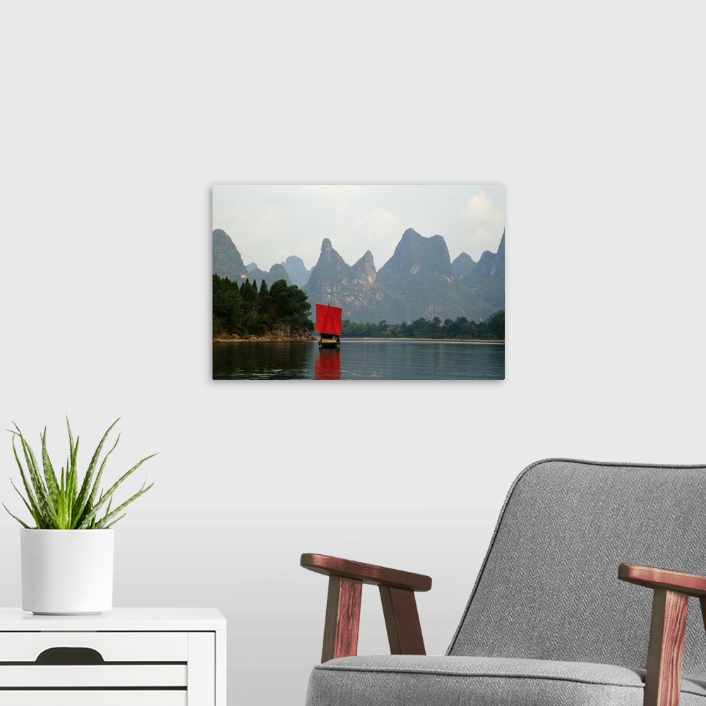A modern room featuring A small boat in a Chinese river is photographed in front of immense cliffs.