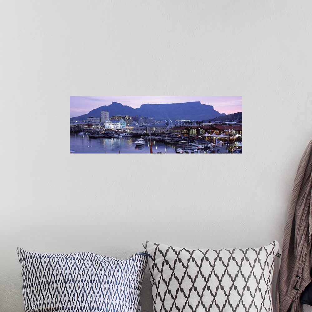 A bohemian room featuring Panoramic photograph of busy boat dock lit up at dusk with skyline and mountains in the distance.