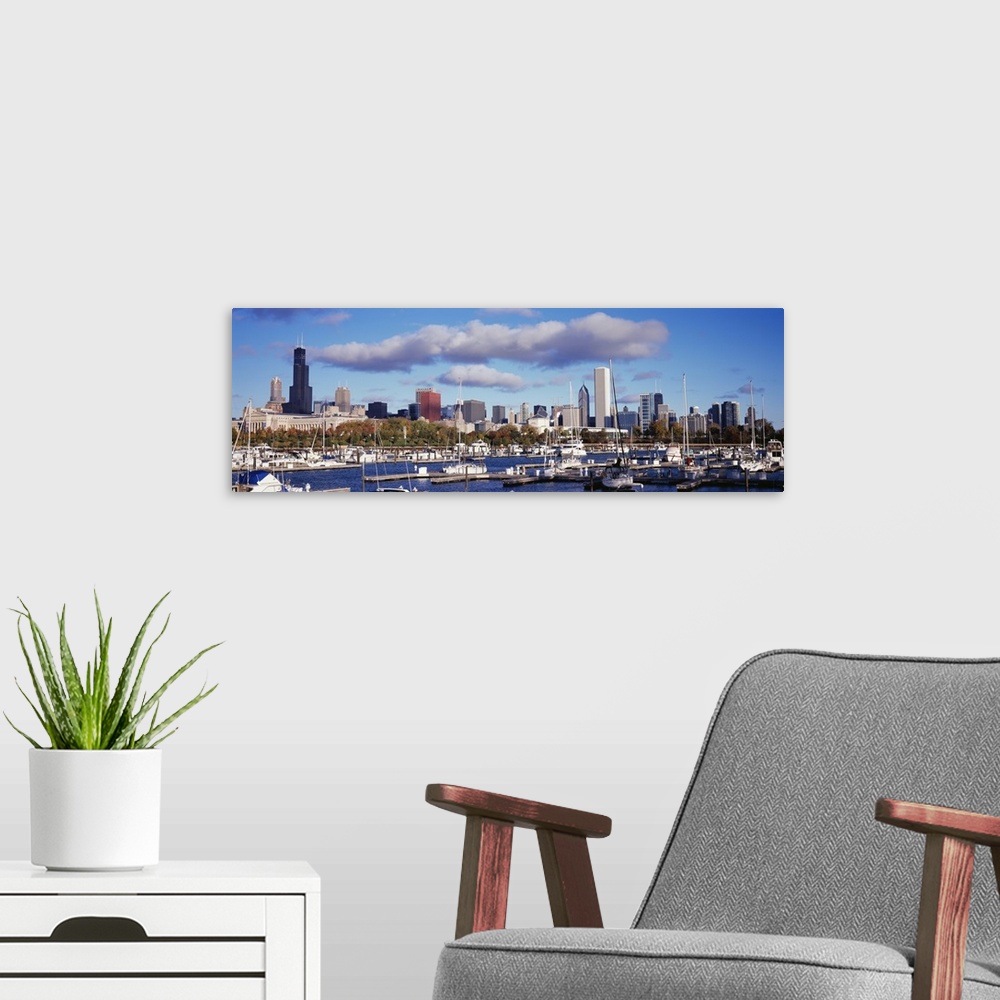 A modern room featuring The Chicago skyline is a backdrop to a wide angle photograph taken of the harbor with several boa...