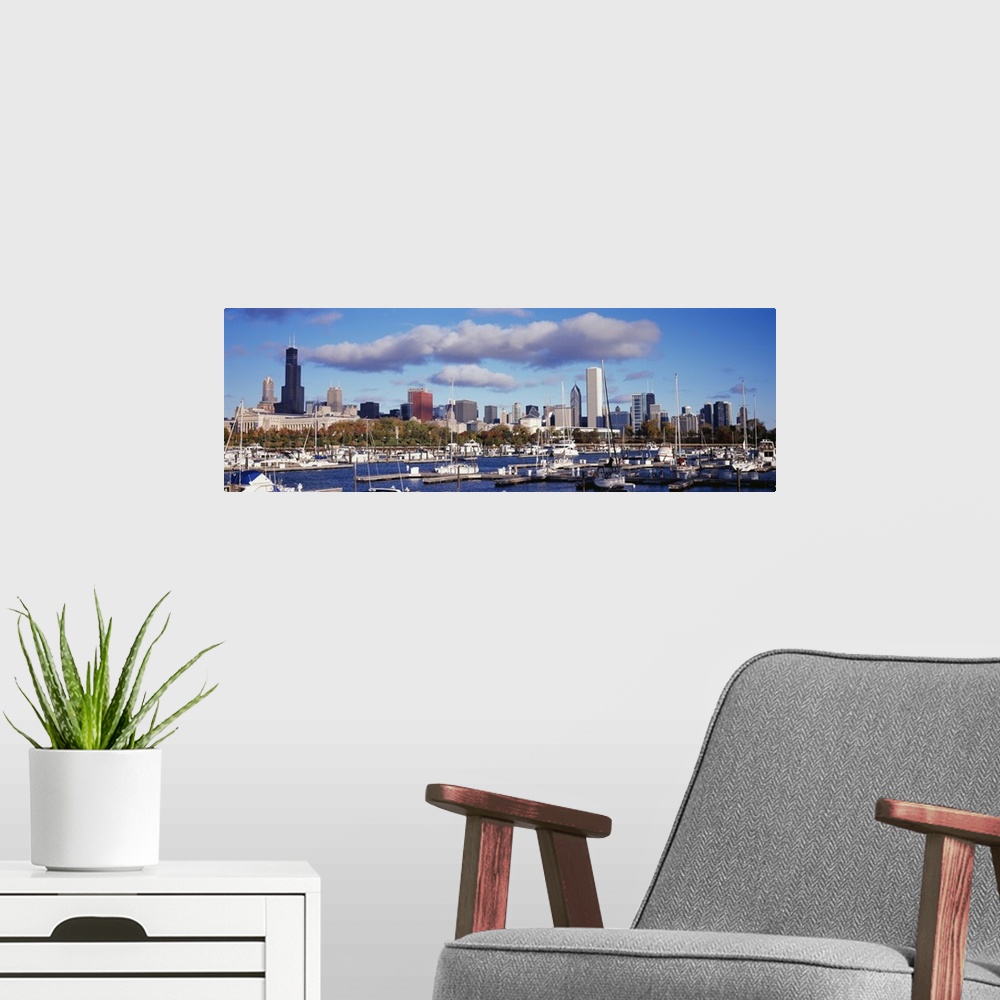 A modern room featuring The Chicago skyline is a backdrop to a wide angle photograph taken of the harbor with several boa...
