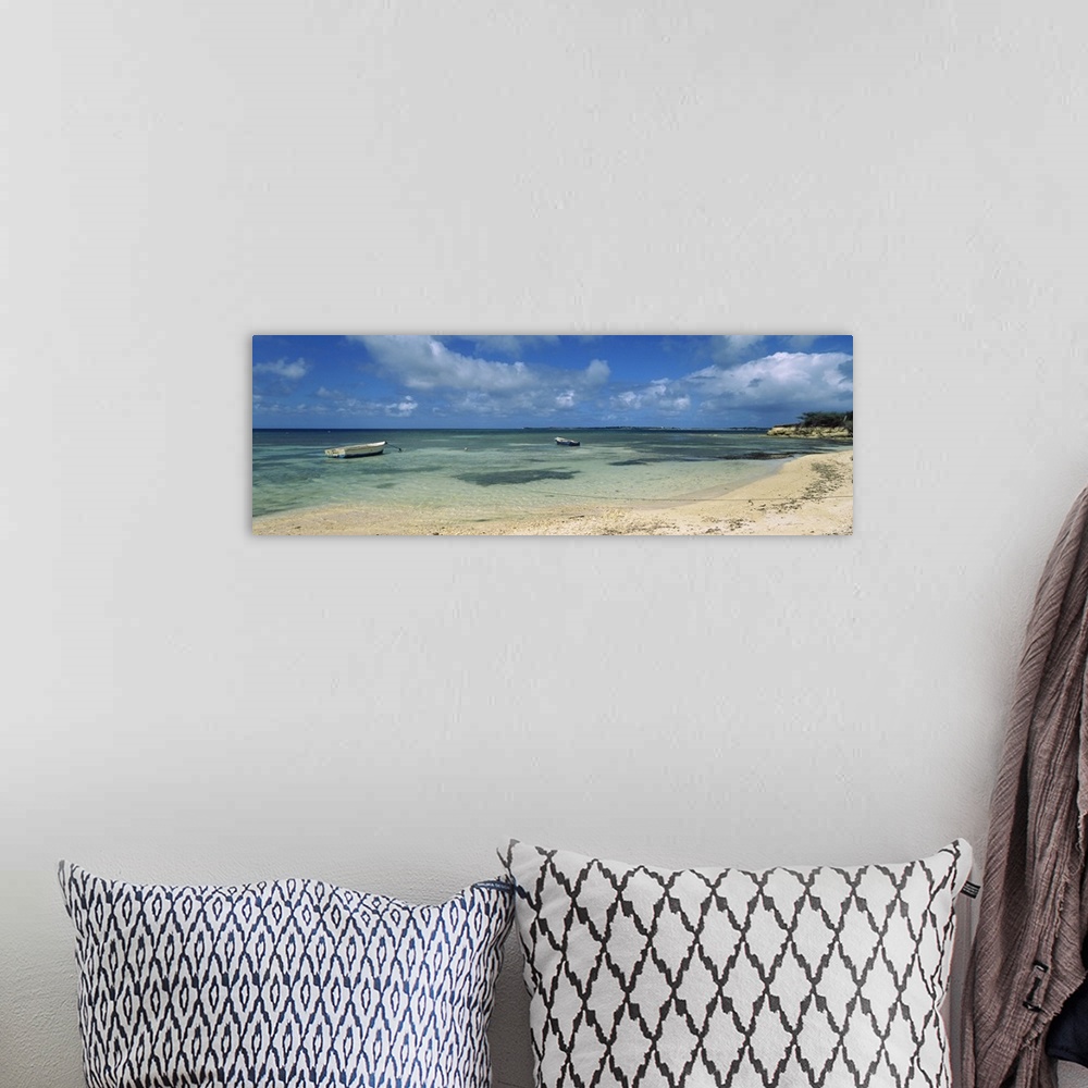 A bohemian room featuring Long horizontal image on canvas of boats floating in the ocean near a shore.