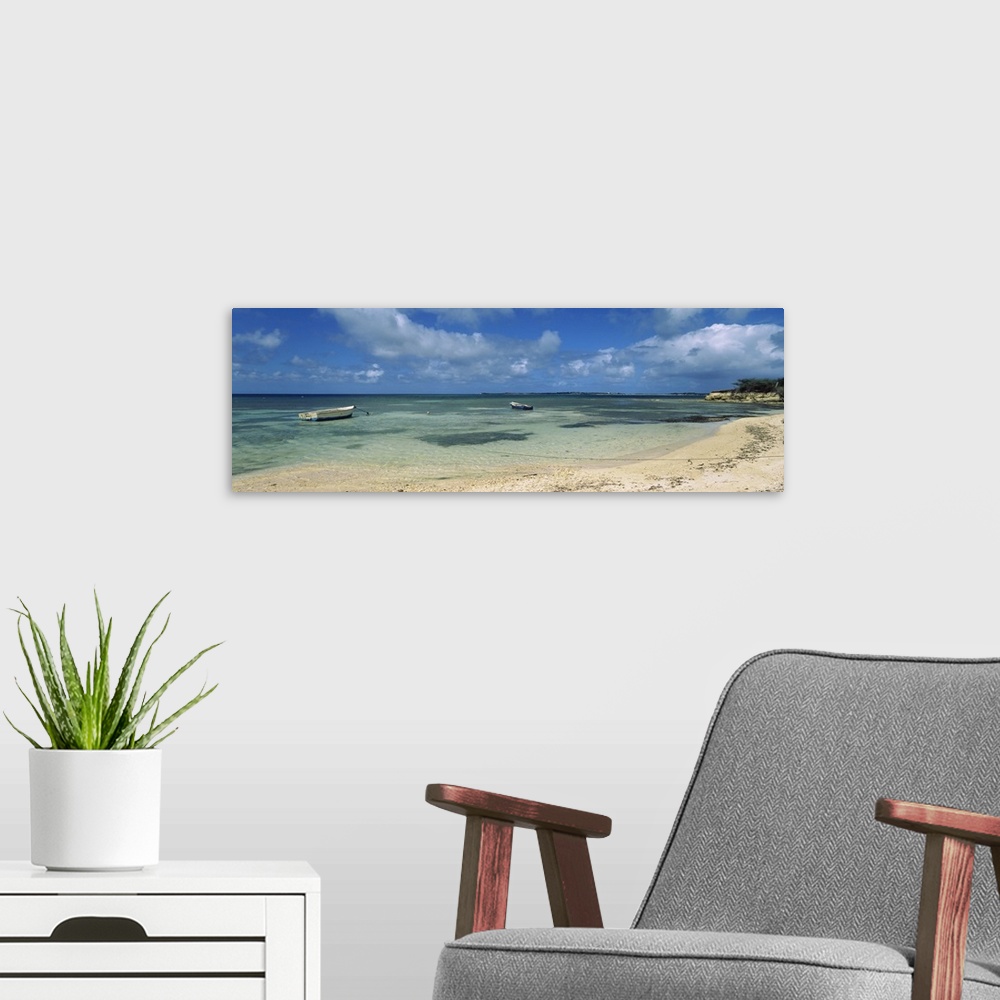 A modern room featuring Long horizontal image on canvas of boats floating in the ocean near a shore.