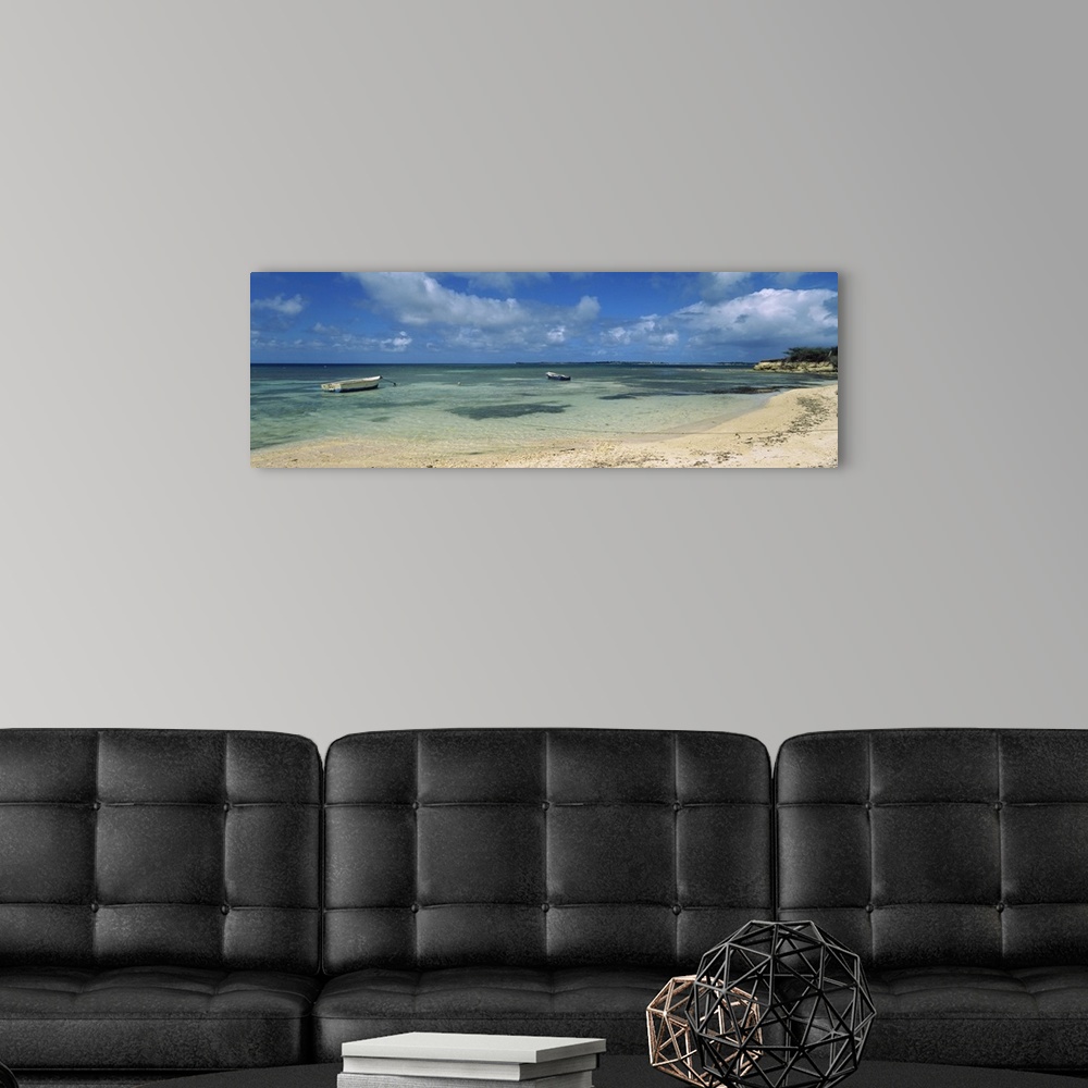 A modern room featuring Long horizontal image on canvas of boats floating in the ocean near a shore.