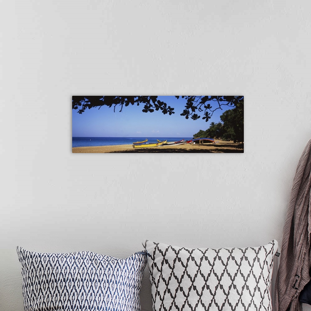 A bohemian room featuring This is a panoramic photograph of boats on the sandy shore and framed with tropical foliage.