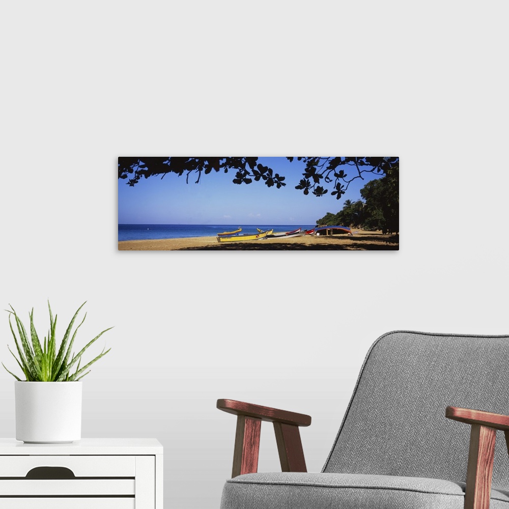 A modern room featuring This is a panoramic photograph of boats on the sandy shore and framed with tropical foliage.