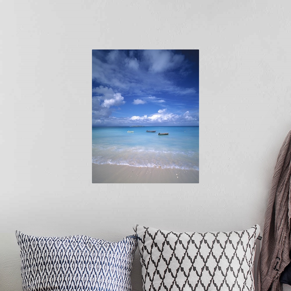 A bohemian room featuring Huge photograph showcases a group of three small water vessels anchored near the shore of a sandy...