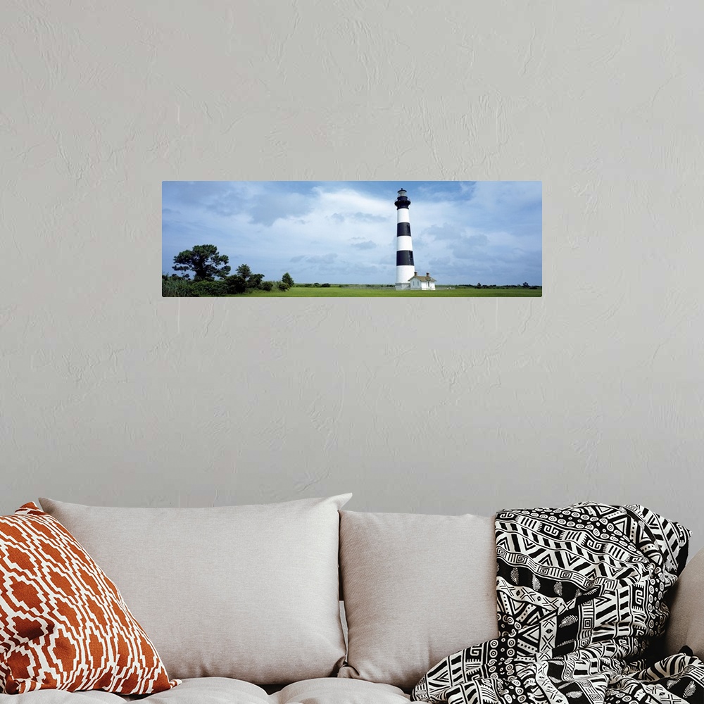 A bohemian room featuring Panoramic photograph of striped Bodie Lighthouse surrounded by a green landscape, beneath a cloud...