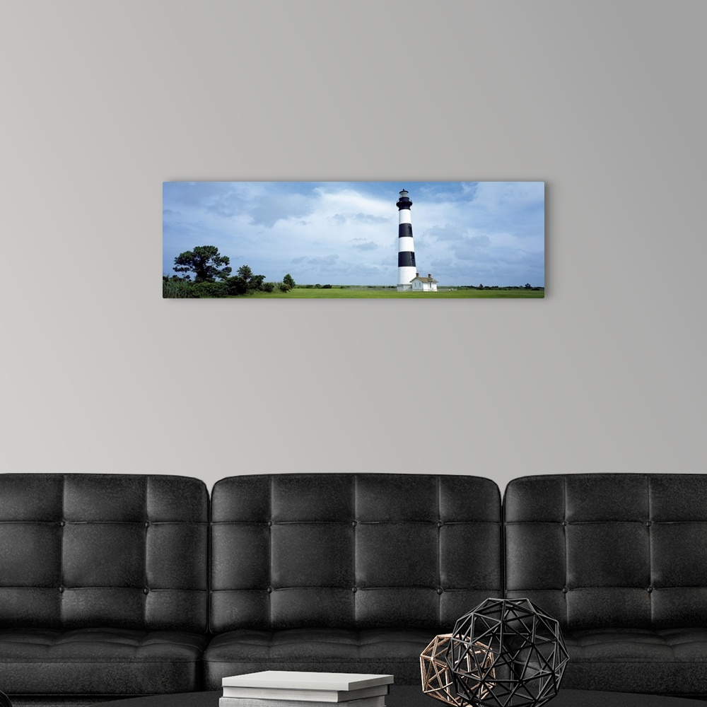 A modern room featuring Panoramic photograph of striped Bodie Lighthouse surrounded by a green landscape, beneath a cloud...