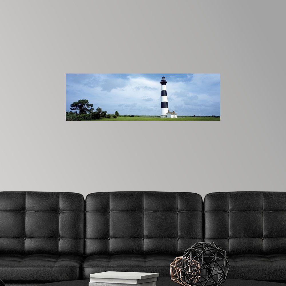 A modern room featuring Panoramic photograph of striped Bodie Lighthouse surrounded by a green landscape, beneath a cloud...