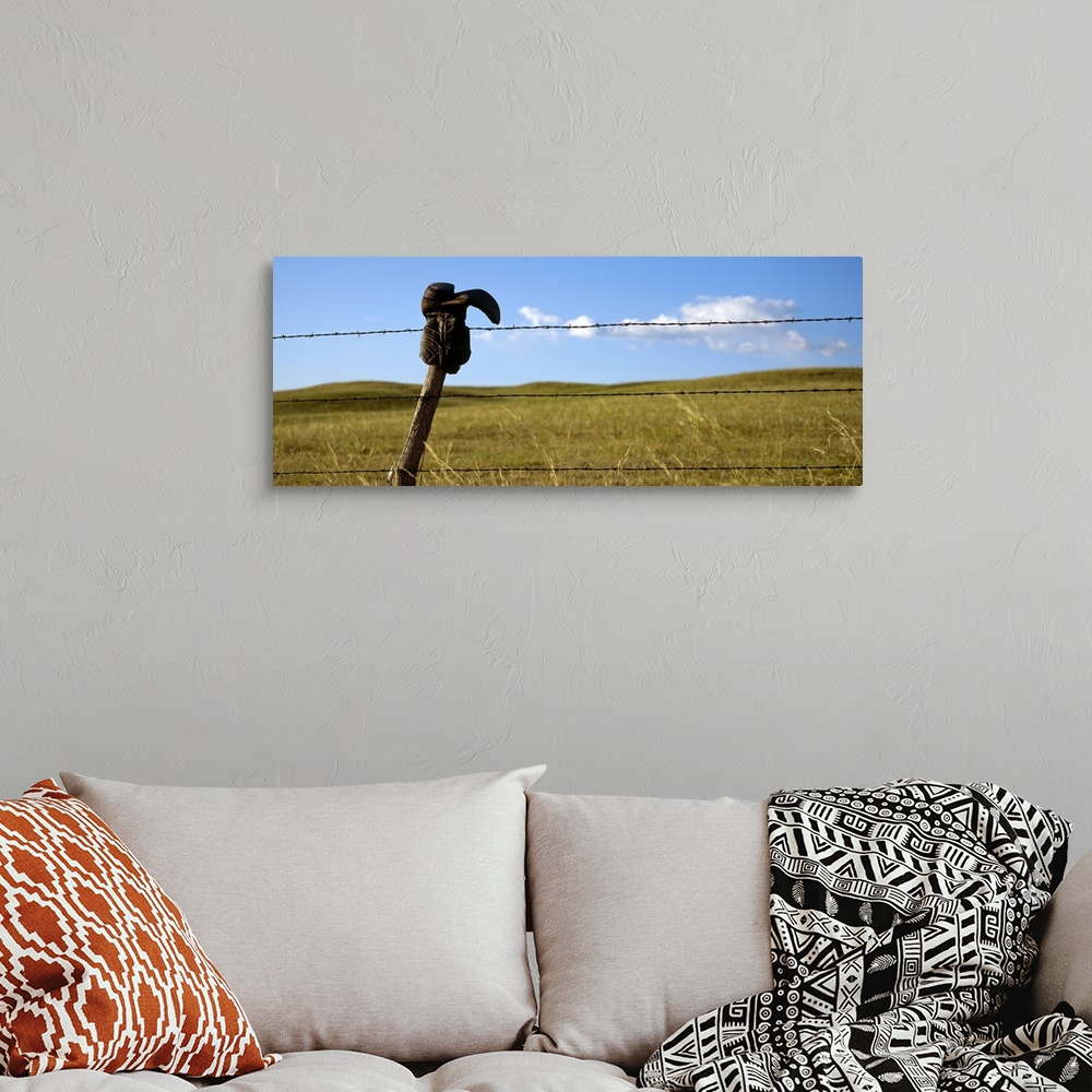 A bohemian room featuring Panoramic photograph of cowboy boot hanging upside down on a cable fence with grass covered hills...