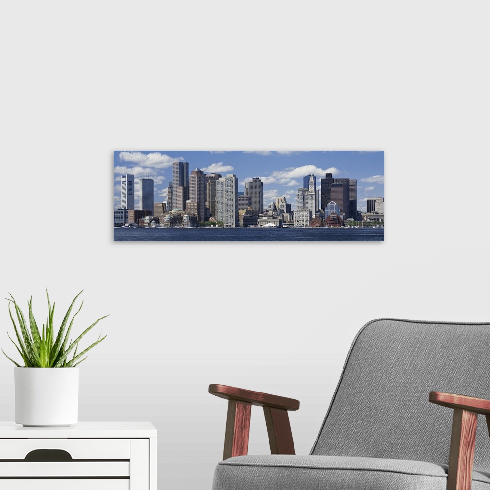 A modern room featuring Panoramic big canvas print of a cityscape along a water front with a blue sky with puffy clouds i...