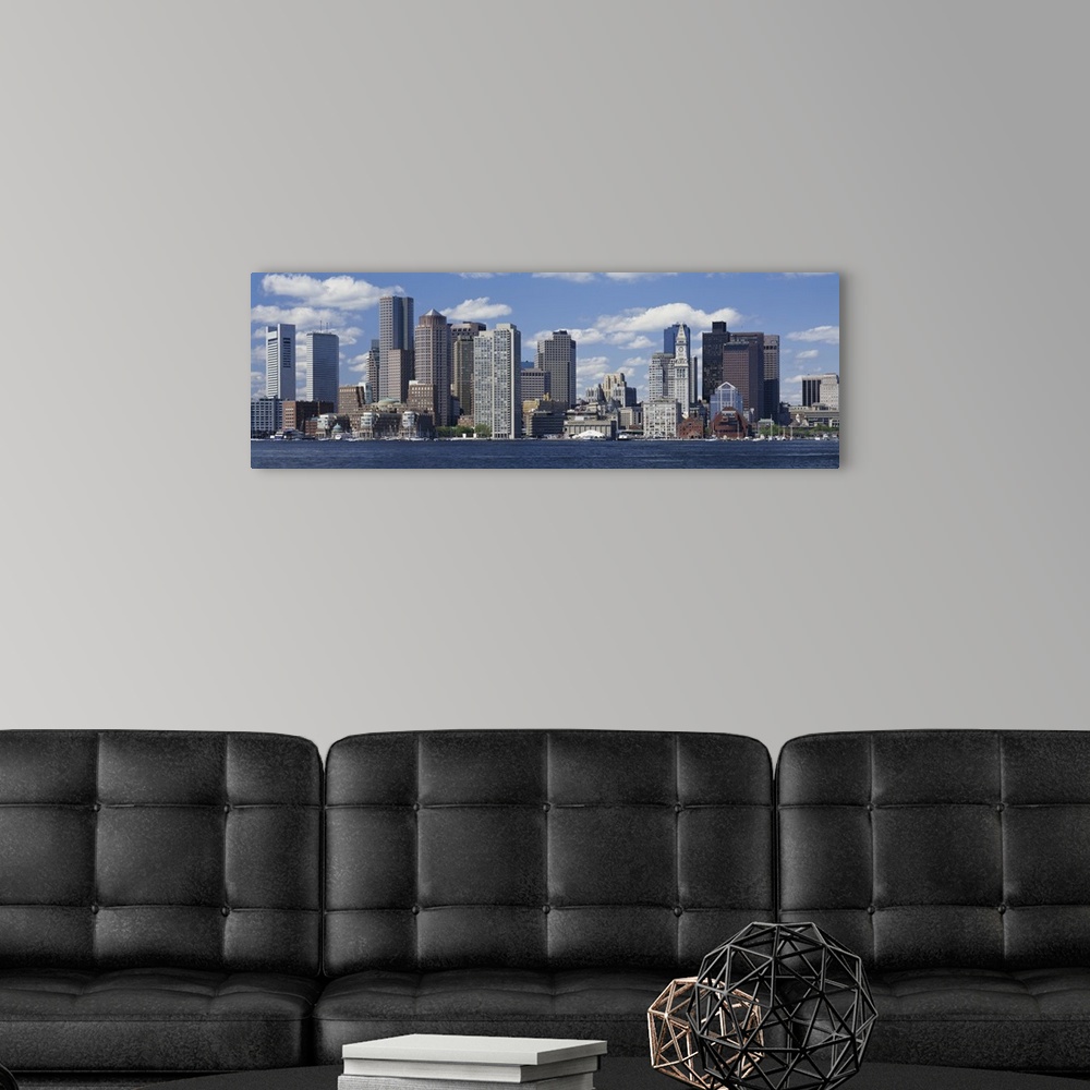 A modern room featuring Panoramic big canvas print of a cityscape along a water front with a blue sky with puffy clouds i...