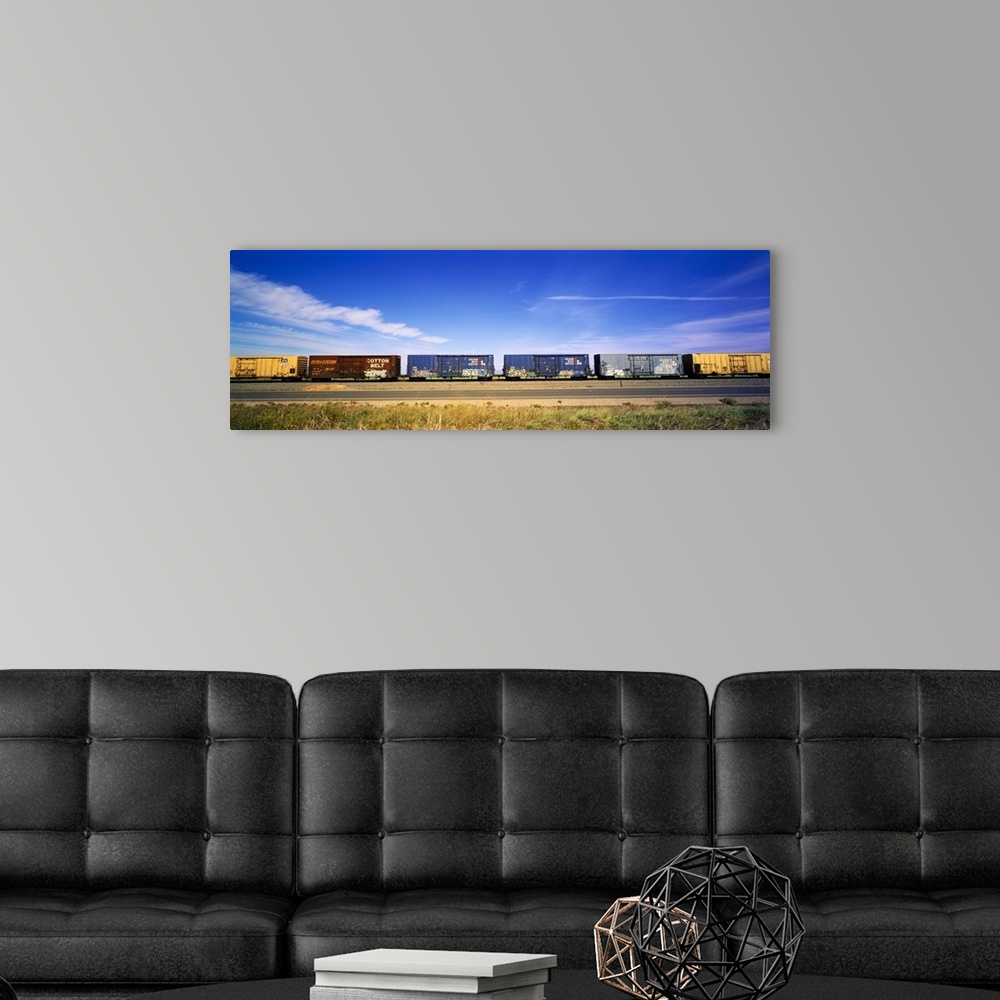 A modern room featuring Panoramic photograph of rusted train cars on a railway under cloudy skies.