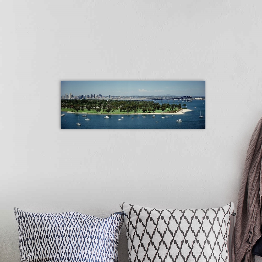A bohemian room featuring Panoramic photograph of many small boats and an area of land with many trees near the bay, next t...