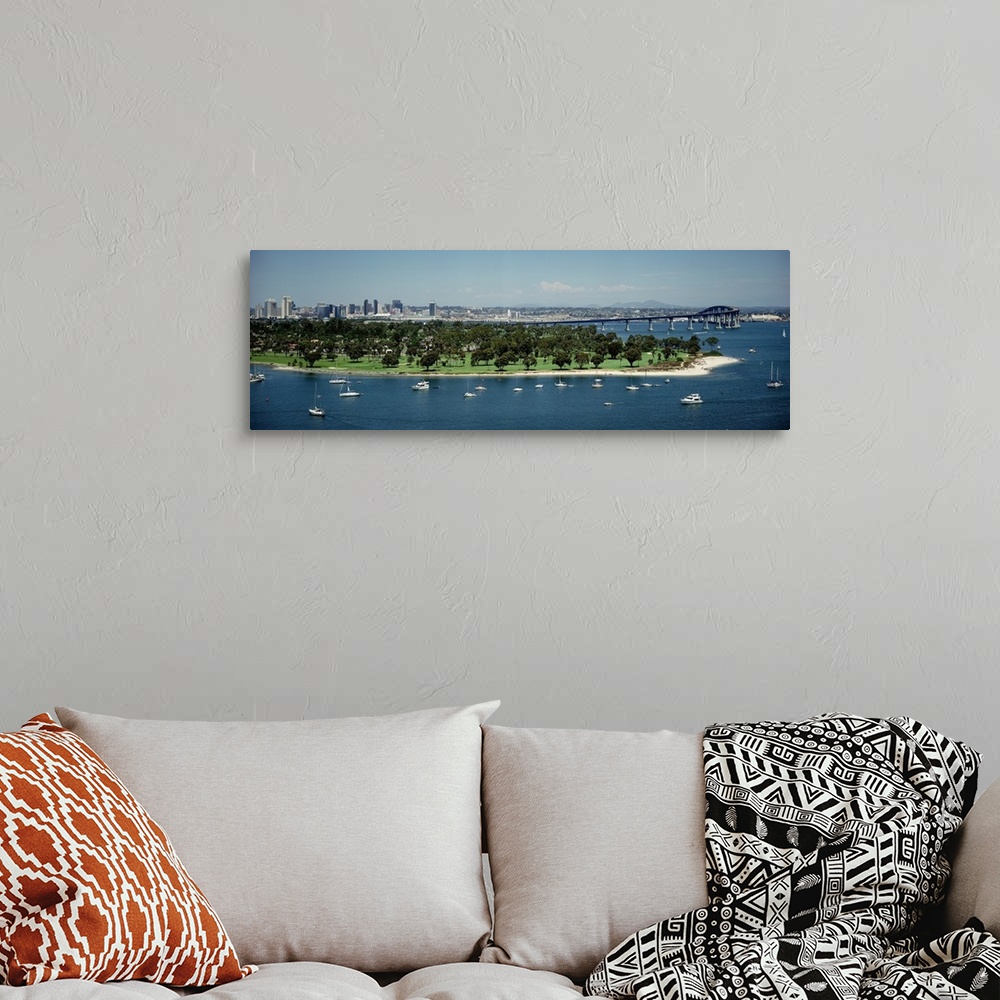 A bohemian room featuring Panoramic photograph of many small boats and an area of land with many trees near the bay, next t...